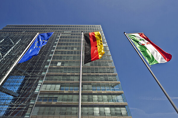 Foto von hohem Gebäude mit drei Fahnen (Europa, BRD; NRW) im Vordergrund;  Foto: Dorothea Näder, LfM